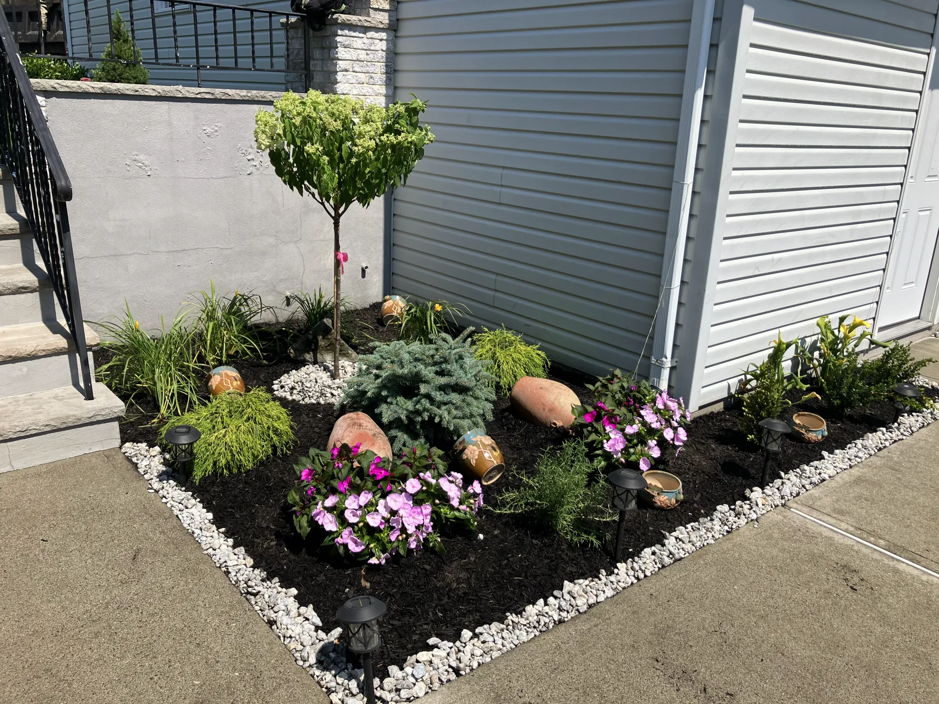Colorful flower garden bed with fresh mulch and river-rock border by D'Luvani Landscaping